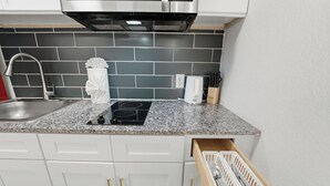 Eine Küche mit Edelstahlarmatur, integriertem Backofen, weißem Handtuchspender und einem Messerblock.