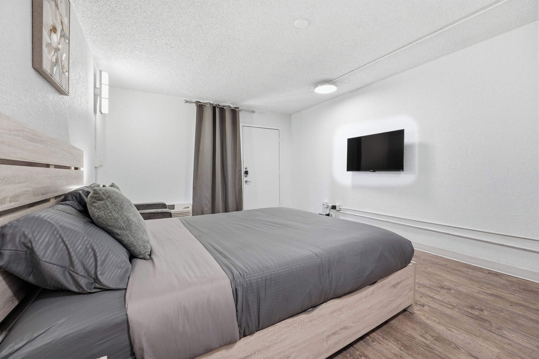 Una camera da letto moderna con un letto, una TV a schermo piatto, una porta e un lampadario.
