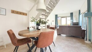 Una sala de estar moderna con comedor, una escalera y vistas al exterior.