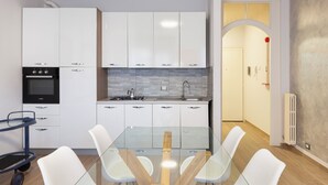 A modern kitchen with white cabinets, a glass table, and white chairs. - The house of the badger (Feriolo)