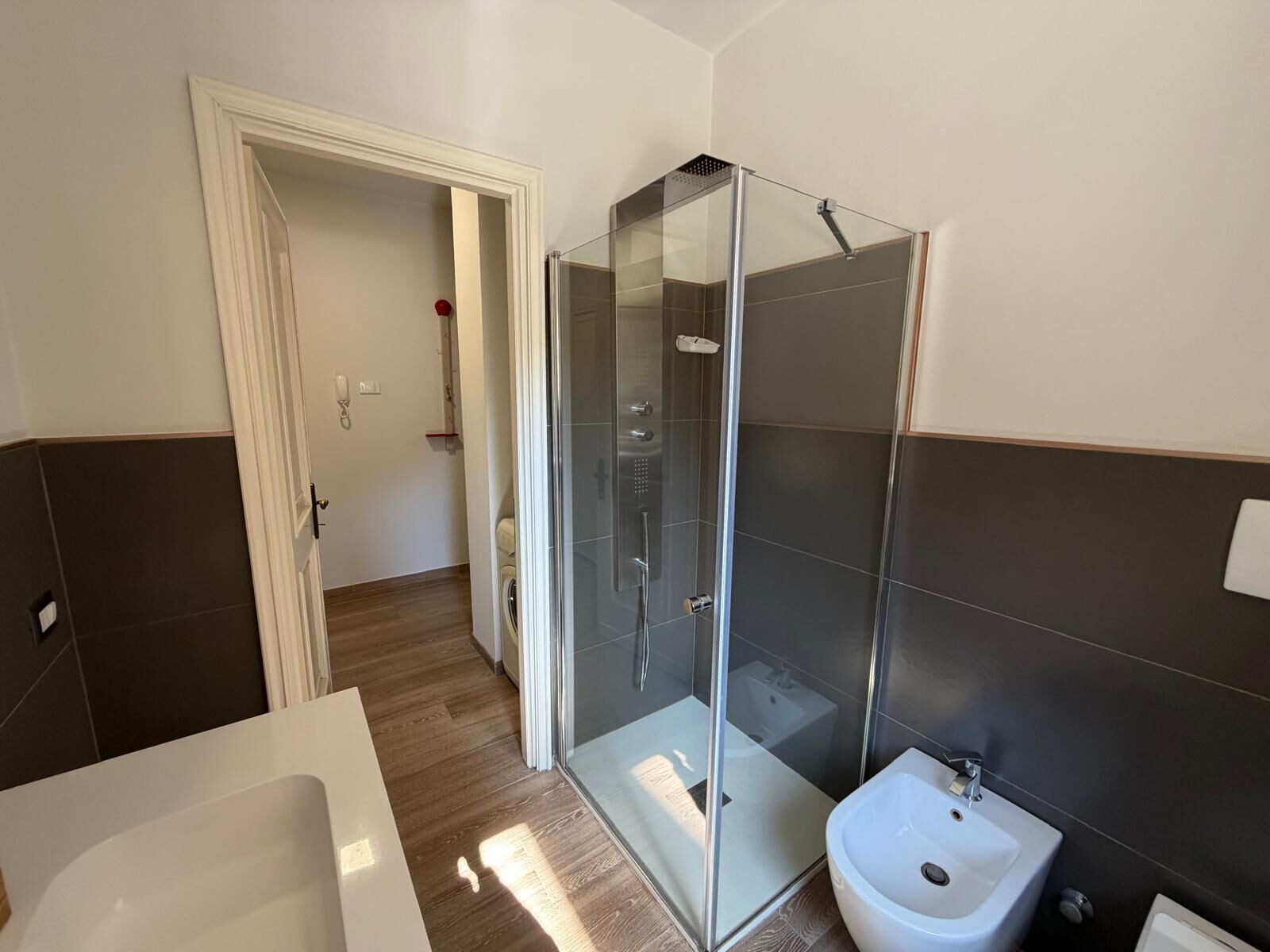 Une salle de bain moderne avec une douche à parois de verre, un lavabo blanc et une baignoire.