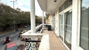 Un balcon donnant sur une rue animée, de grandes fenêtres et un sol carrelé.