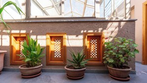 A building exterior with three potted plants in front of wooden doors with decorative glass panels. - Riad House of Calligraphy Marrakech (Marrakech)