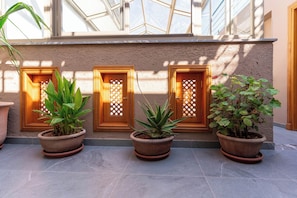 Fachada de edificio con tres macetas frente a puertas de madera con paneles de vidrio decorativos.