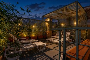 Un patio con sillones de descanso, una pérgola y plantas en macetas.