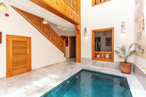 Una piscina con una escalera de madera y una planta en maceta.