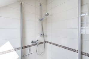 A modern shower with a glass enclosure, chrome fixtures, and a tiled wall with a decorative border.