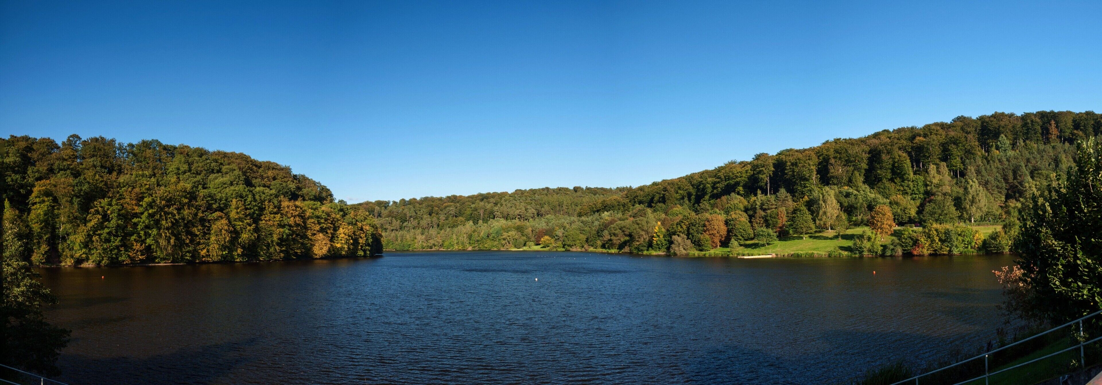 Ein See, umgeben von bewaldeten Hügeln.