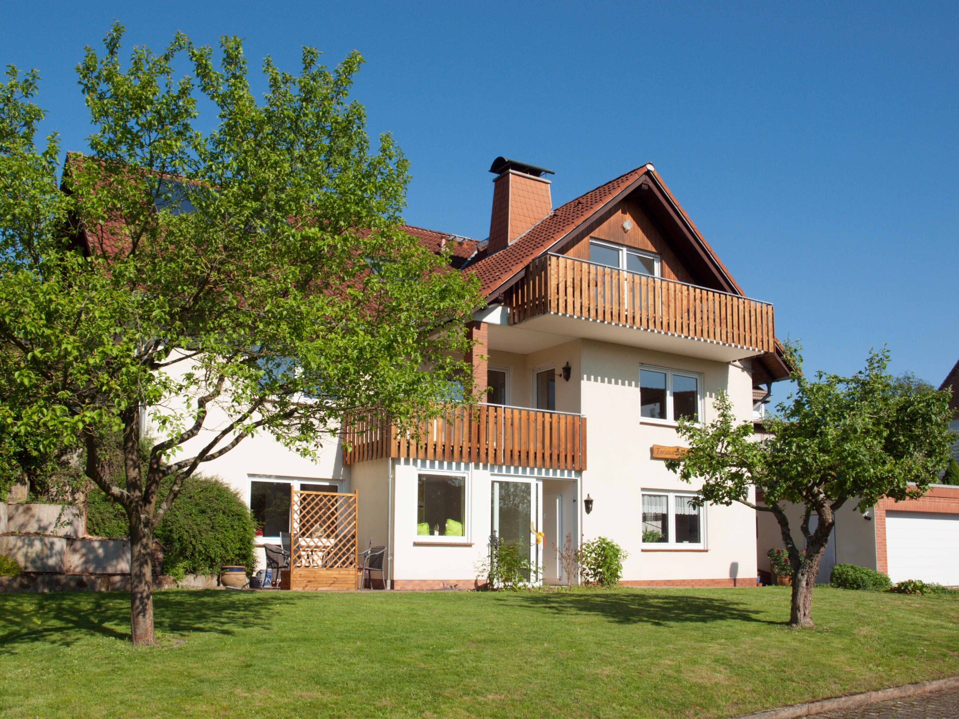 A two-story house with a balcony, a door, and a window.