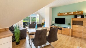 Uma sala de estar moderna com área de jantar, televisão e um armário de madeira.