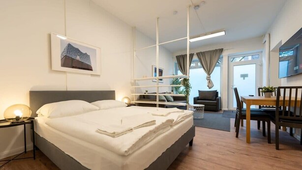 Ein modernes Hotelzimmer mit einem großen Bett, einem Schreibtisch, einem Sessel und einem Fernseher.