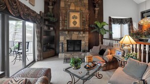 Una sala de estar acogedora con chimenea de piedra, asientos cómodos y vistas a través de puertas de vidrio grandes.