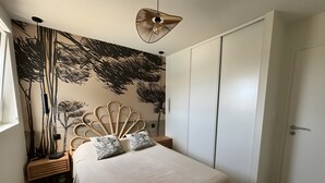 Een slaapkamer met een bed, hoofdbord, kledingkast, nachtkastje en een lamp.