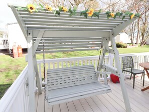 A white outdoor swing set with a bench underneath, surrounded by a white railing, and decorated with sunflowers. - Sunflower Retreat, Caravan 61 (Morpeth)
