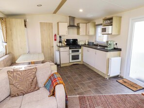 A compact kitchenette with a stove, microwave, and small refrigerator. - Sunflower Retreat, Caravan 61 (Morpeth)