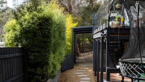 A garden pathway with stepping stones, a wooden fence, and a bench. - Lovely Beach Cottage Heart of Rye (Rye)