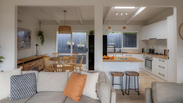A modern kitchen with white cabinets, a central island, and pendant lighting. - Lovely Beach Cottage Heart of Rye (Rye)