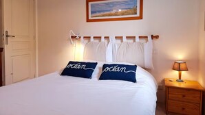 Ett sovrum med en säng, två kuddar med texten ”hav” på, ett sängbord med en lampa, en dörr och en inramad tavla på väggen.