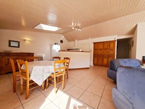 Ein Essbereich mit Tisch und Stühlen, eine Küche mit Schränken und eine Wohnbereich mit einer Couch.