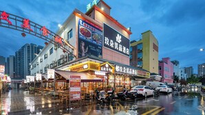 A multi-story building with a restaurant on the ground floor, a large sign advertising a hotel, and several parked vehicles. - Medo Boutique Hotel Shenzhen Bao'an (Shenzhen)