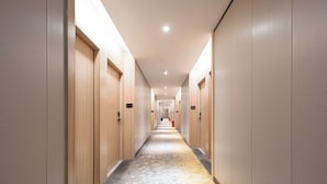 A hotel hallway with wooden doors, a patterned carpet, and a light-colored floor. - Medo Boutique Hotel Shenzhen Bao'an (Shenzhen)