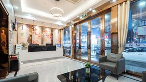 A hotel reception area with a marble reception desk, a seating area with a glass table, and large windows offering a view of the street. - Medo Boutique Hotel Shenzhen Bao'an (Shenzhen)