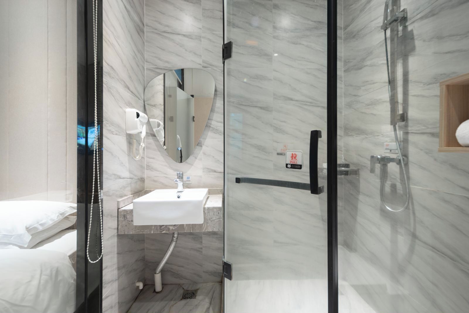 A modern bathroom with a glass shower enclosure, a white sink, and a mirror.