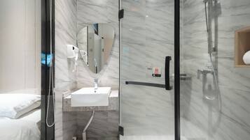 A modern bathroom with a glass shower enclosure, a white sink, and a mirror.