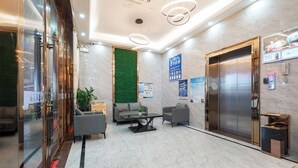 A modern lobby with marble flooring, a green vertical garden, seating area, and an elevator. - Medo Boutique Hotel Shenzhen Bao'an (Shenzhen)