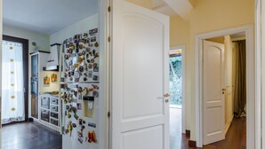 Eine Küche mit einem Kühlschrank, der mit Magneten bedeckt ist, Holzboden und einer Tür zu einem anderen Raum.