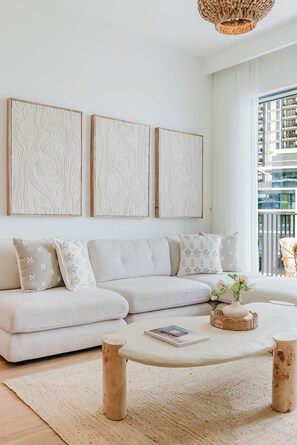 A modern living room with a sofa, coffee table, and artwork on the wall. - PVH - Refined 2BR - Island Park 2 (Dubai)