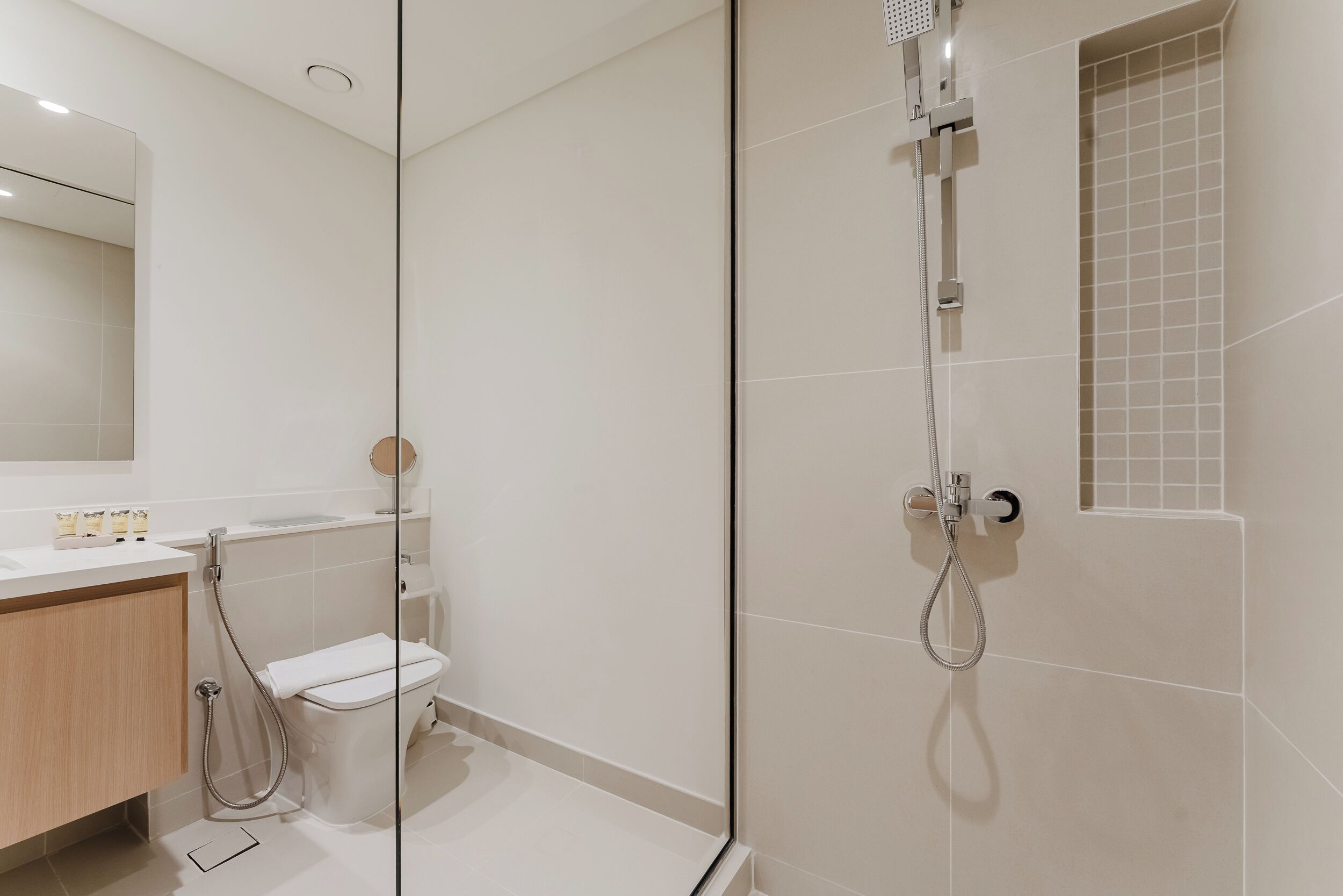 Une salle de bain moderne avec une douche à parois de verre, des toilettes et un lavabo équipé de produits de toilette.