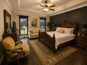 A bedroom with a large bed, a ceiling fan, a window with a view, a sofa, and a chair. - Spacious 4BR Retreat | Sleeps 8 • 2 Kings + 2 Queens (Corpus Christi)