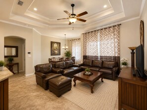 A living room with a sectional sofa, a coffee table, a TV, and a ceiling fan. - Spacious 4BR Retreat | Sleeps 8 • 2 Kings + 2 Queens (Corpus Christi)