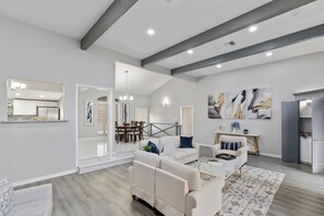 A spacious living area with a high ceiling, a dining area, and a kitchen visible through an open doorway. - This fully renovated 3BR | 2BA home (2,000+ sq ft) offers the perfect mix of modern design, comfort, and space—ideal for families, groups, or extended stays.<br><br>🛏️ Bedrooms & Sleeping Spaces<br>• 2 King bedrooms 👑<br>• 1 Queen bedroom 🛌<br>• 1 (Corpus Christi)