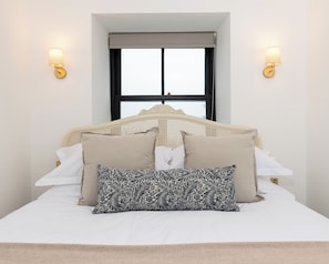 A bed with a headboard, pillows, and two wall-mounted lamps. - Storytellers at Isay | Luxe Skye Coastal Stay (Waternish)