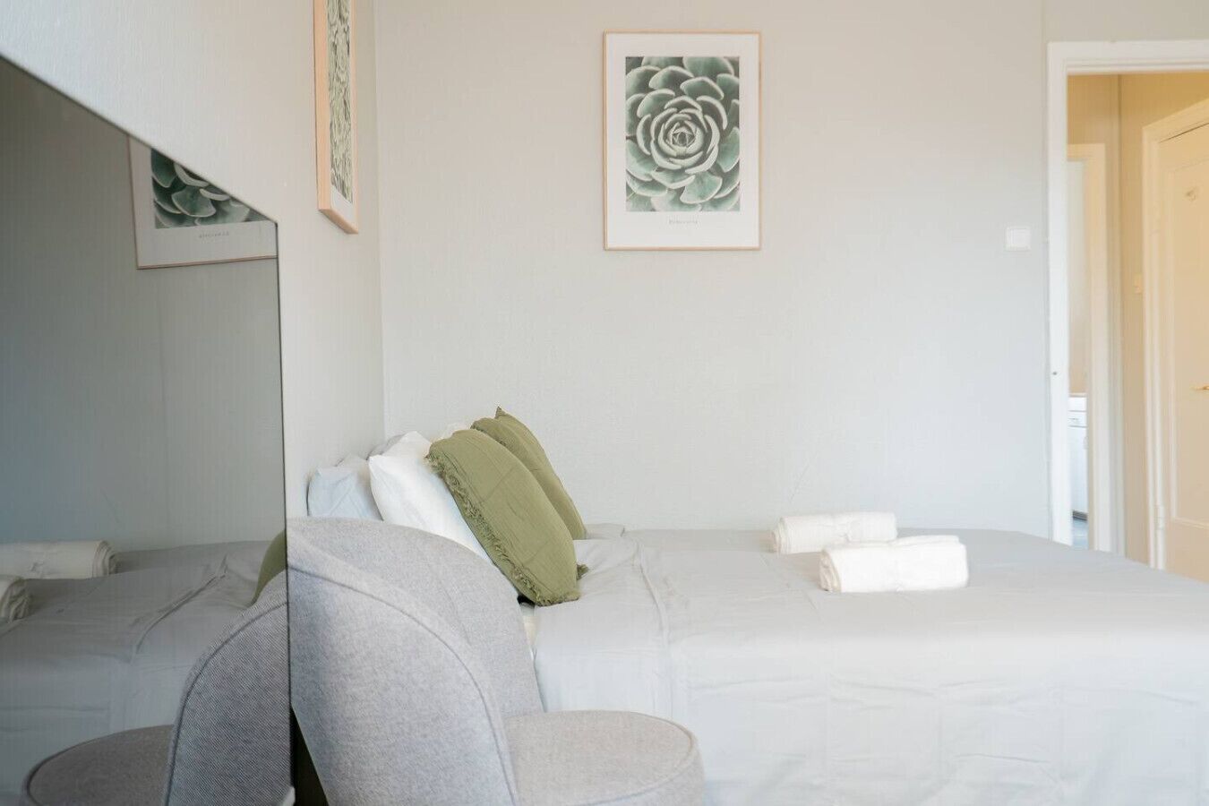 A hotel room with a bed, a chair, and a framed artwork on the wall.