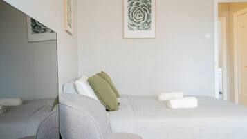 A hotel room with a bed, a chair, and a framed artwork on the wall.