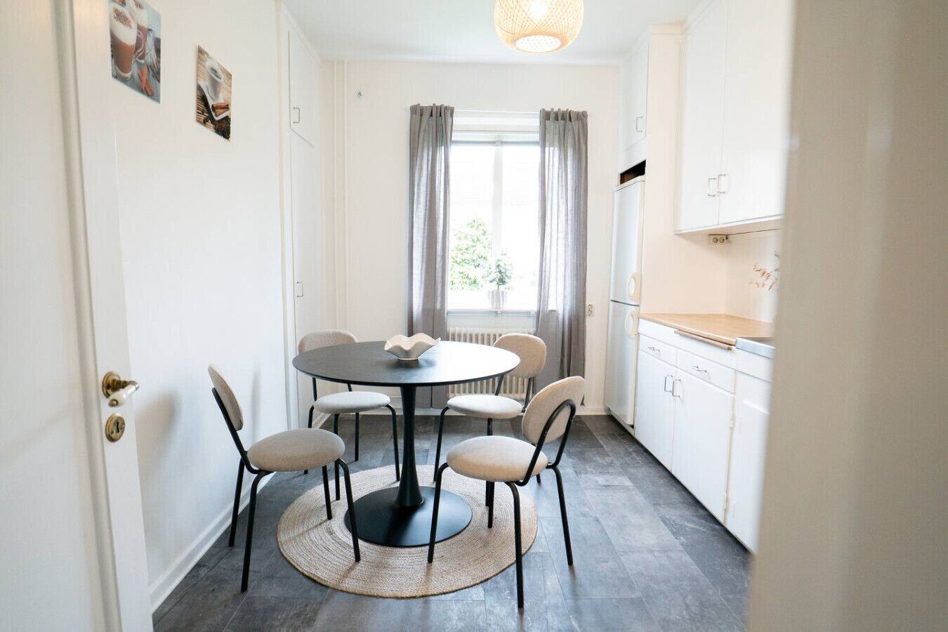 Un comedor con una mesa redonda, seis sillas, un tapete tejido y una ventana con cortinas.