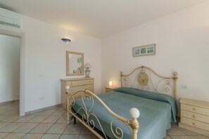 Un dormitorio con cama, cómoda, mesita de noche y lámpara de pared.