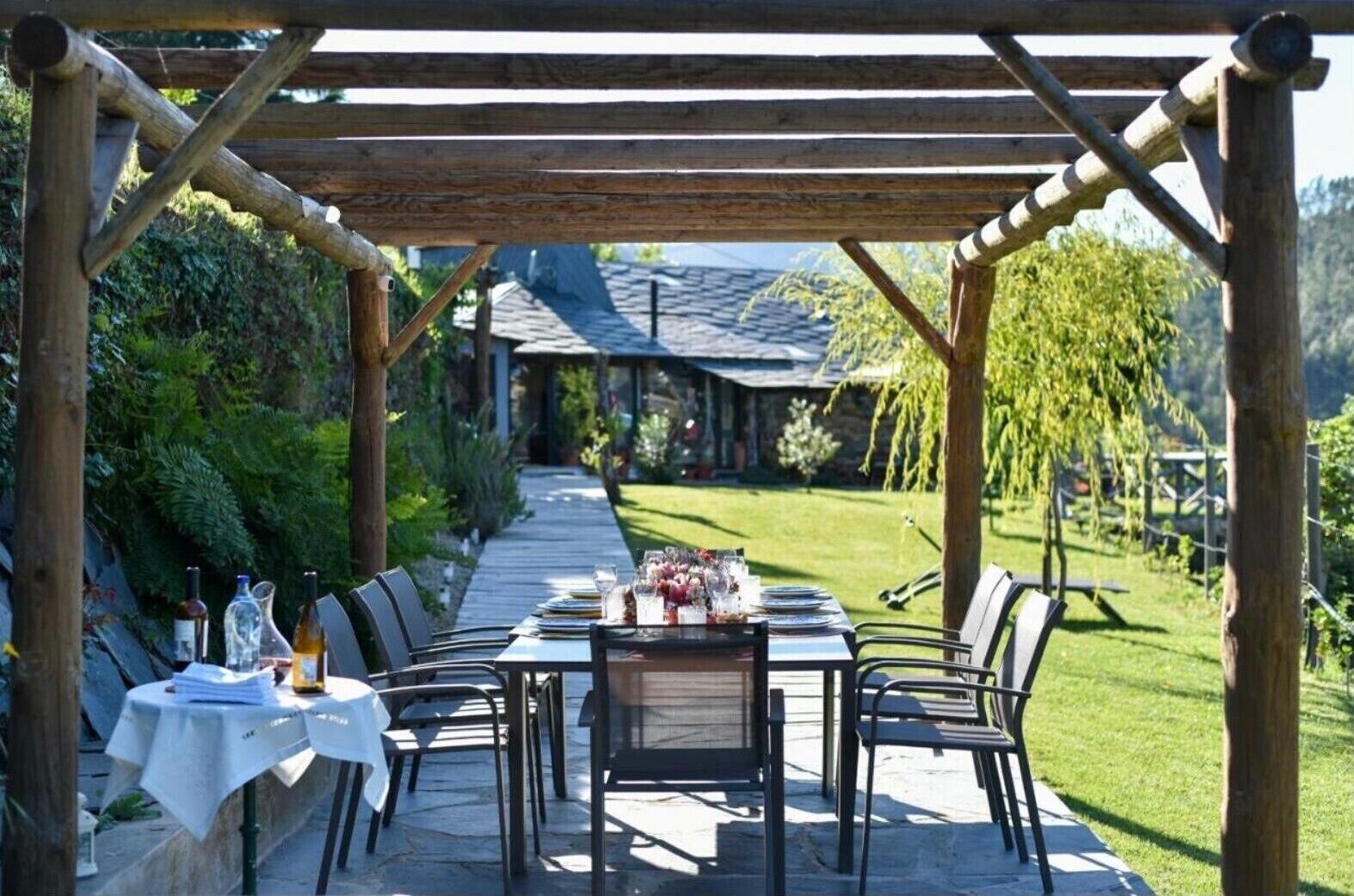 An outdoor dining area with a pergola, tables set with white tablecloths, and chairs.