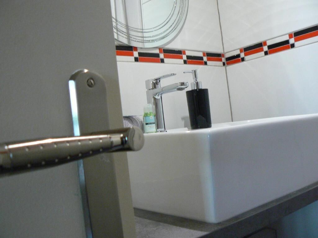 Ein Badezimmer mit einem weißen Waschbecken, einem Spiegel und einer gefliesten Rückwand.
