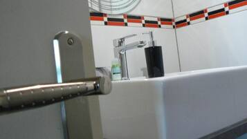 Ein Badezimmer mit einem weißen Waschbecken, einem Spiegel und einer gefliesten Rückwand.