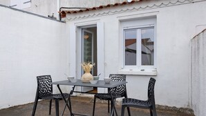 A white building with a tiled roof, a table with chairs, and a window with a white frame. - Victor Studio – 200 m from the Beach (La Tranche-sur-Mer)