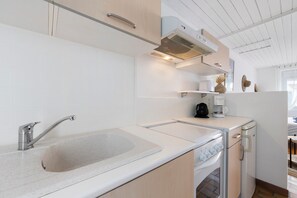 A modern kitchen with a built-in sink, stainless steel faucet, and a compact stove. - Victor Studio – 200 m from the Beach (La Tranche-sur-Mer)