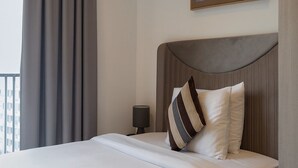 A neatly made bed with a white duvet, a striped pillow, and a rolled towel. - Enjoy Luxury living on a budget at the heart of Accra (Accra)