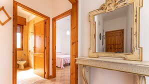 Een gang met houten deuren naar een badkamer en een slaapkamer.
