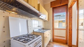 Een keuken met een gasfornuis, spoelbak en houten kastjes.