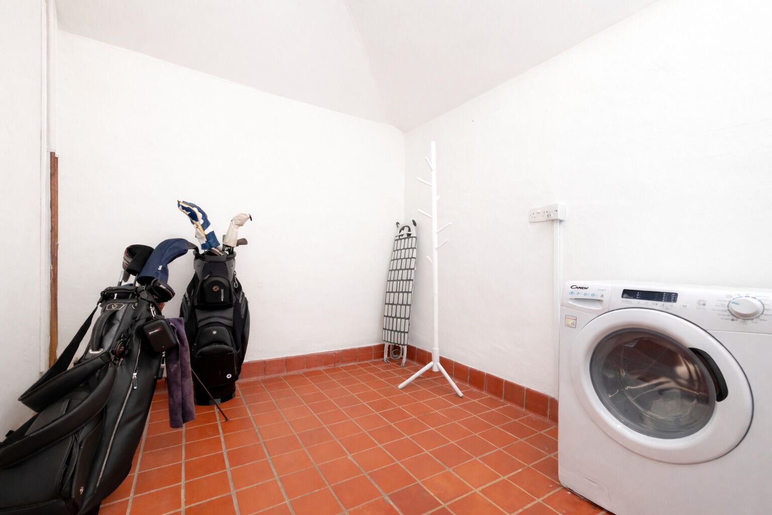 A laundry room with a washing machine, a drying rack, and two bags of luggage.