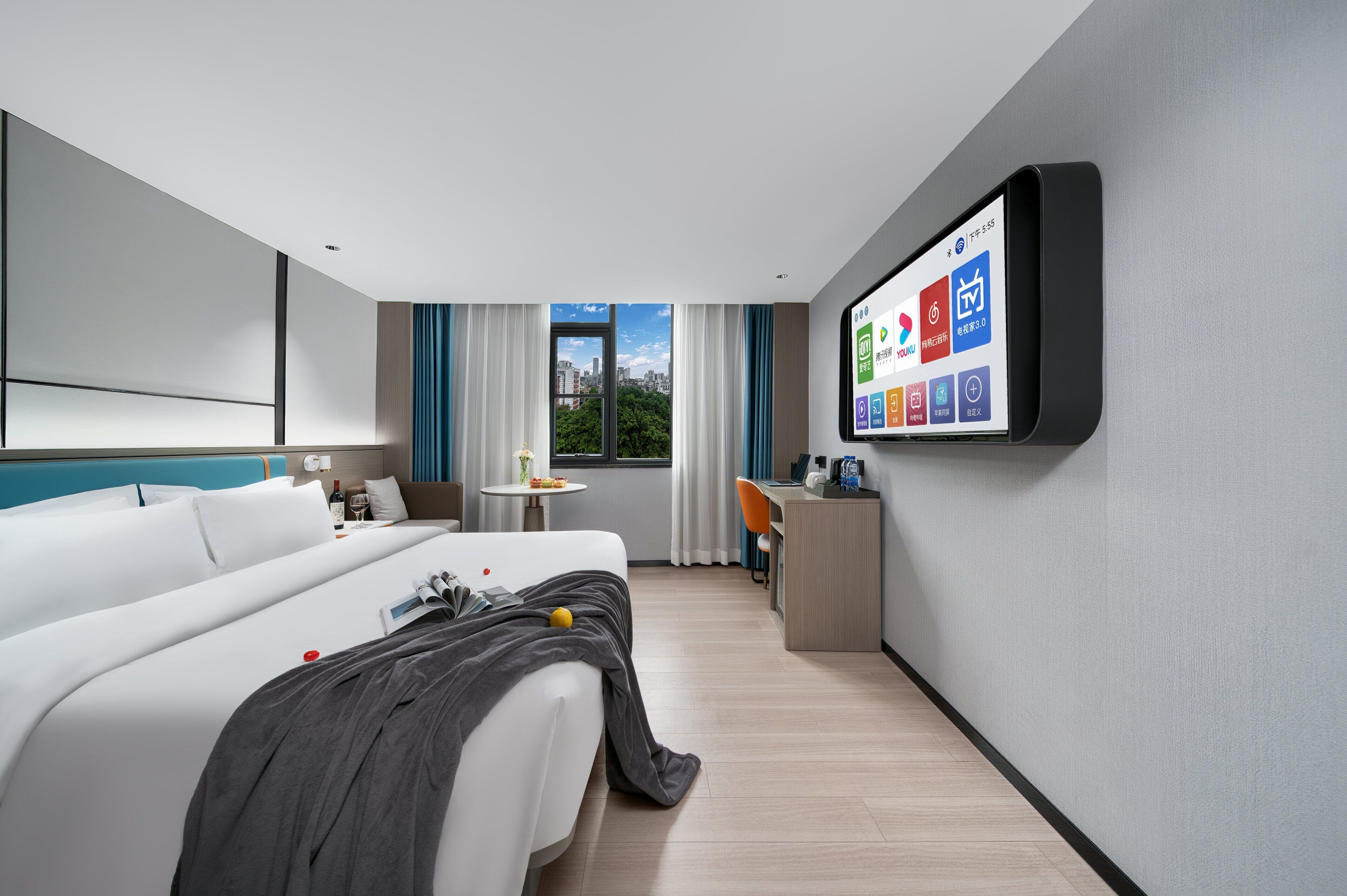 Ett modernt hotellrum med en säng, ett skrivbord och en stor skärm som visar hotellets appar.